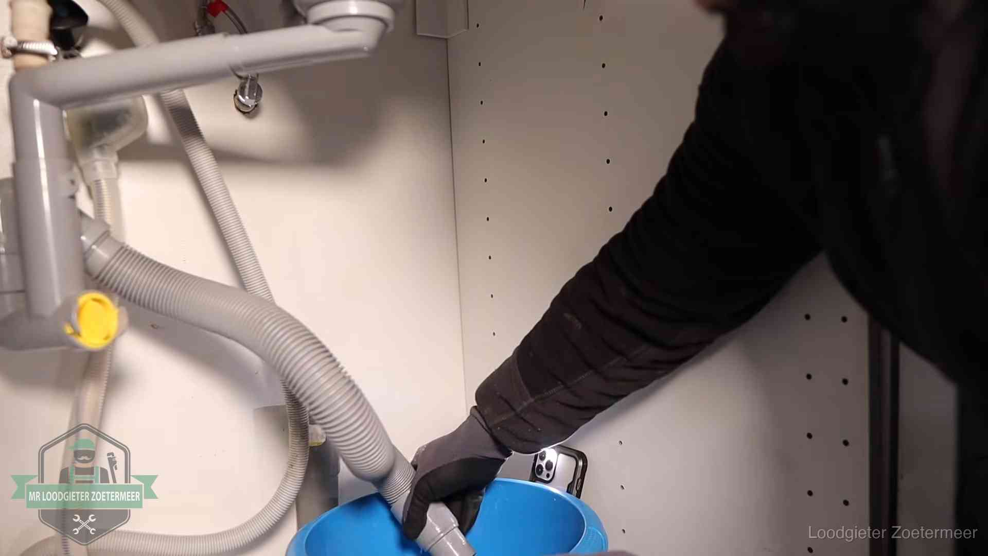 Afvoerslang loopt leeg in een emmer onder de gootsteen in Zoetermeer, een klus die je zelf kunt doen