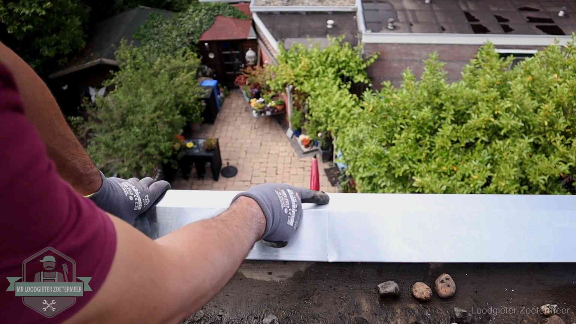 Vakman plaatst een daktrim op de dakrand van een woning in Zoetermeer