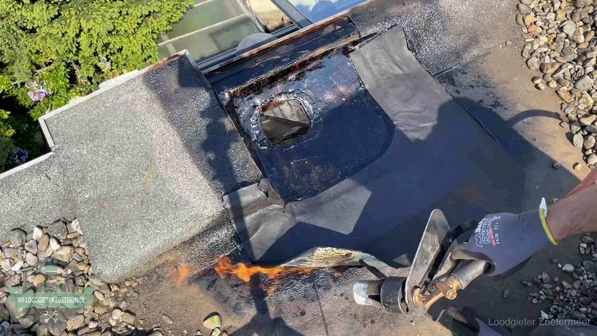 Dakdekker brandt bitumen rond een doorvoer tijdens een daklekkage-reparatie in Zoetermeer