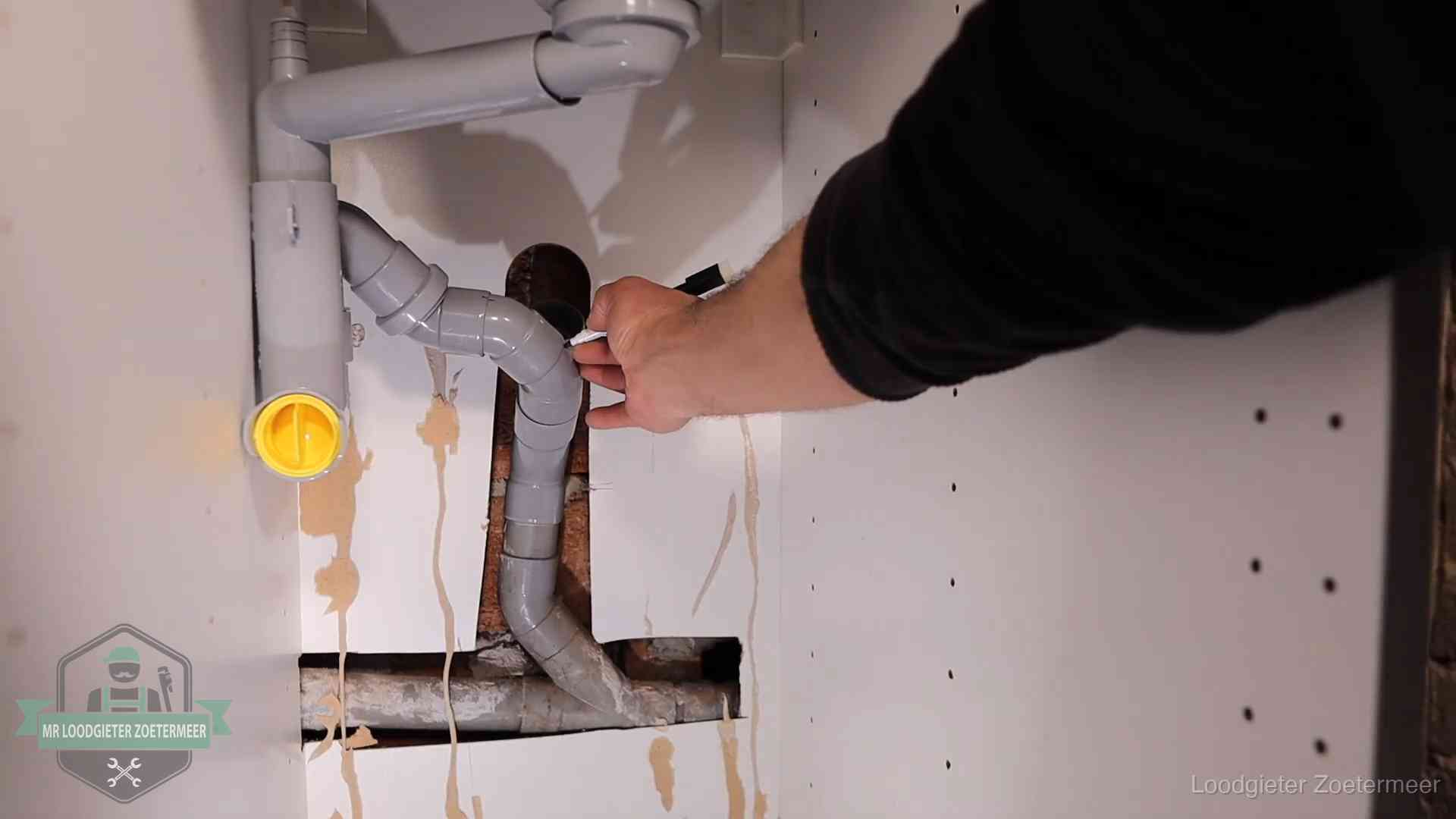 Loodgieter markeert een pvc-afvoerbuis onder een gootsteen in Zoetermeer