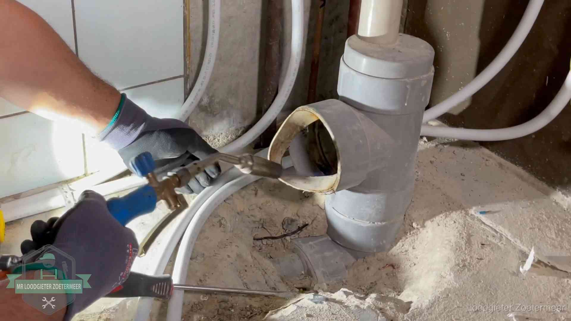Loodgieter werkt met brander en messing kraanwerk aan leidingen in Zoetermeer