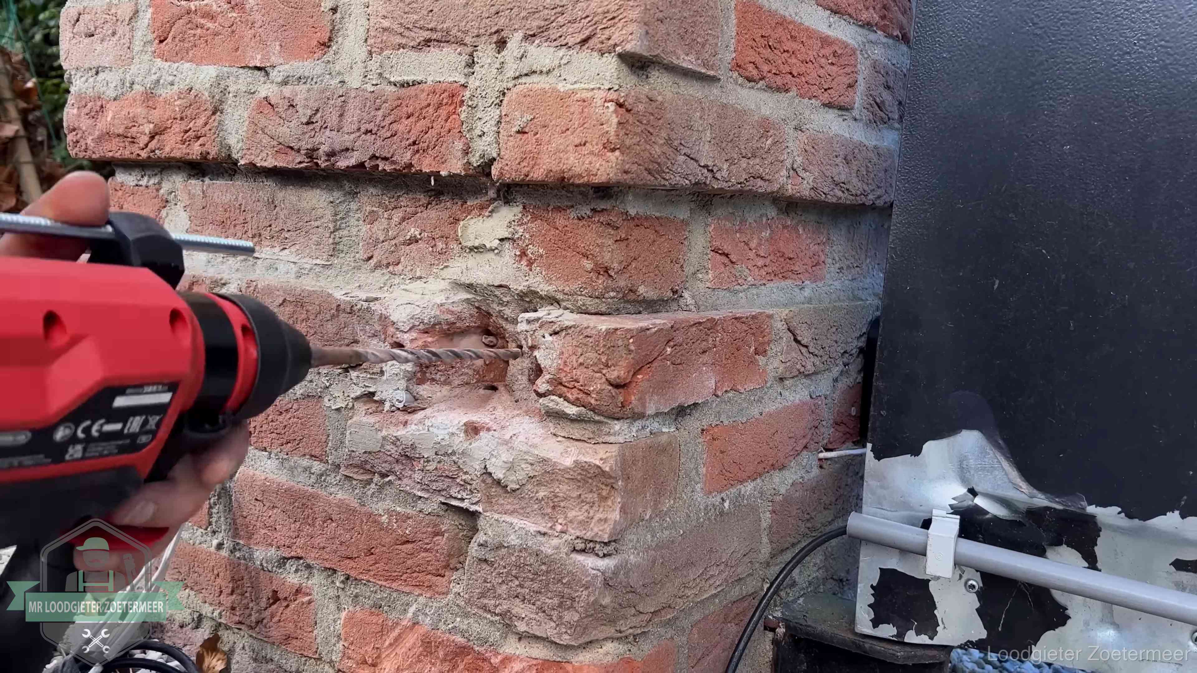 Vakman boort in de buitenmuur van een woning in de regio Zoetermeer