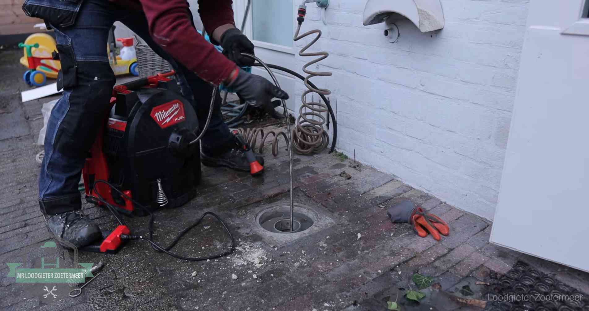 Ontstoppingsputje in de bestrating naast de gevel van een woning in Zoetermeer