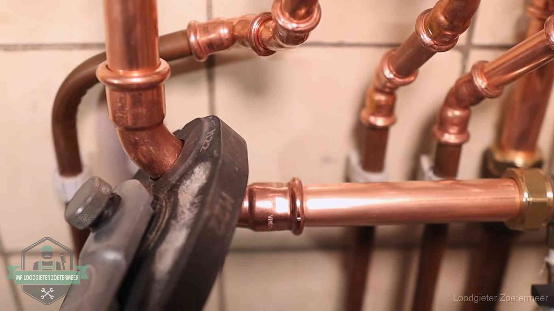 Persmachine perst een koperen fitting op nieuw leidingwerk in Zoetermeer