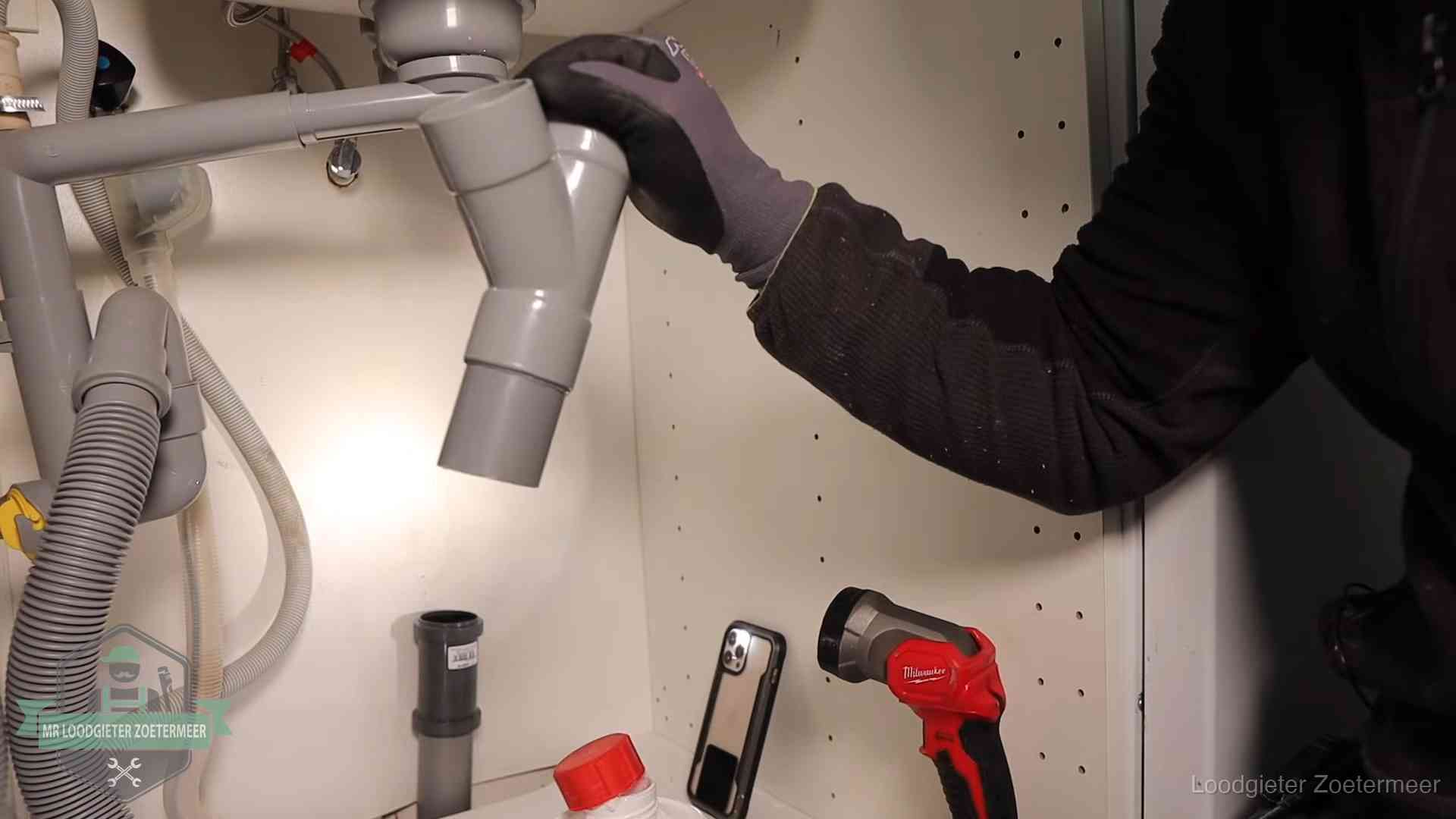 Loodgieter demonteert het sifon- en afvoerwerk onder een gootsteen in Zoetermeer bij stankklachten