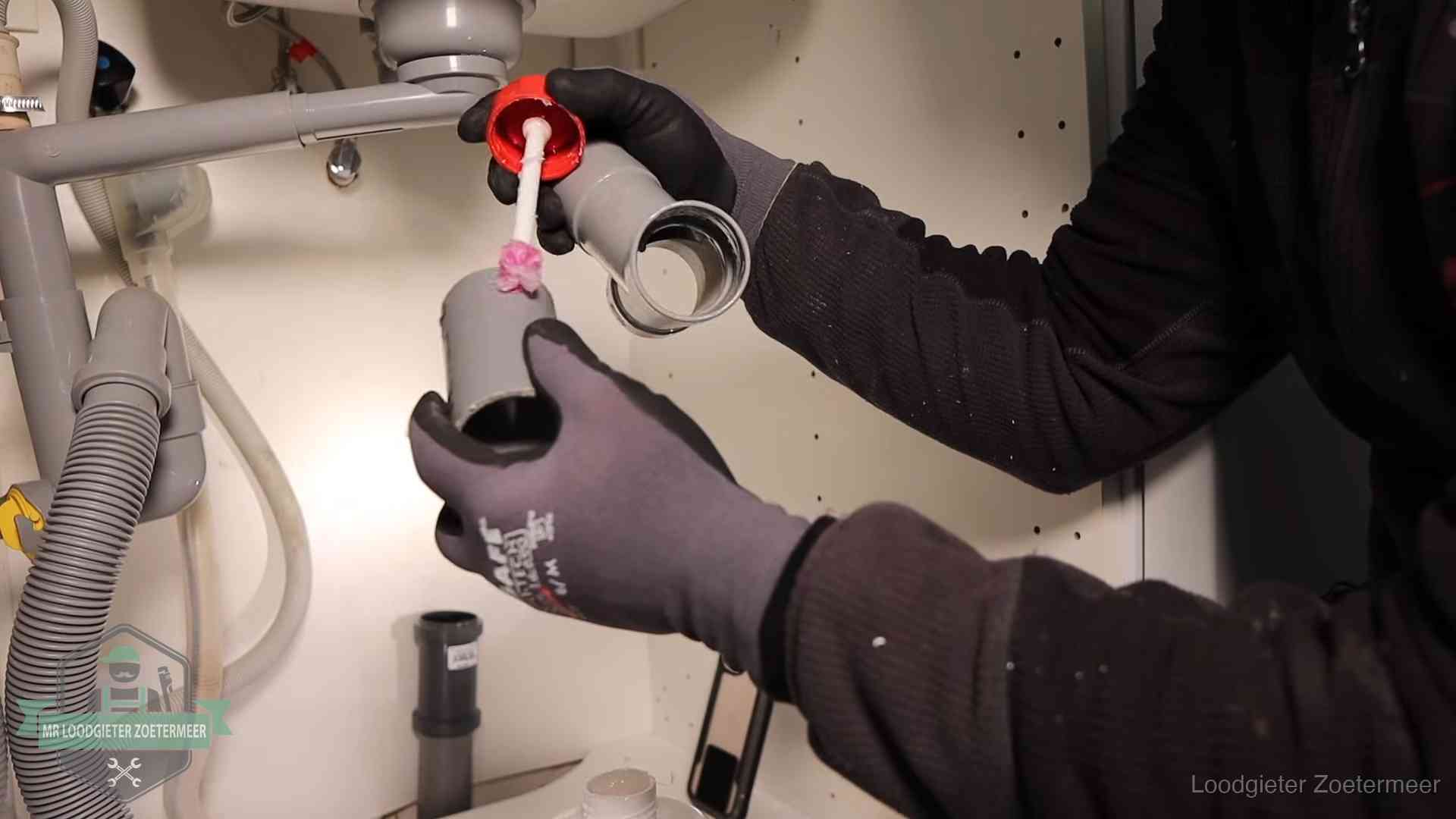 Loodgieter demonteert en reinigt de sifon onder een keukenkast in Zoetermeer
